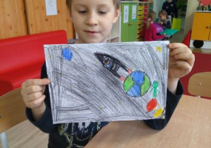 Chłopiec prezentuje rysunek przedstawiający Świat Wyobraźni